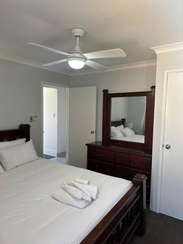 a bedroom with a bed with a ceiling fan and a mirror at Slate House Caversham in Caversham
