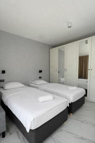 two beds in a room with white walls at Apartamenty Odrodzenia 11 in Szczytno