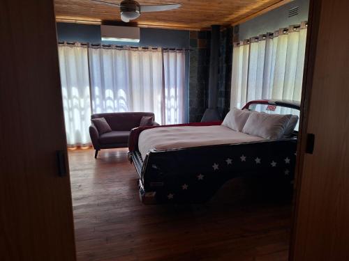 a bedroom with a bed and a chair and windows at The V8 House in Sutherland
