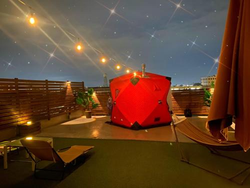 a large red umbrella on a balcony at night at space AJITO in Kofu
