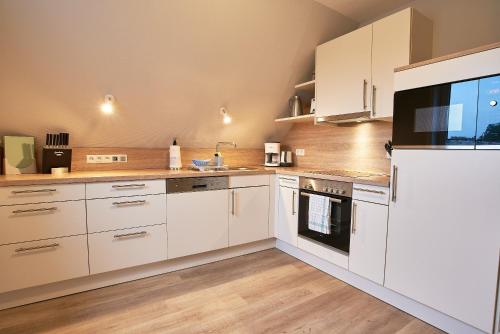 a kitchen with white cabinets and a large appliance at Südstern OG, Schwalbenweg in Wyk auf Föhr