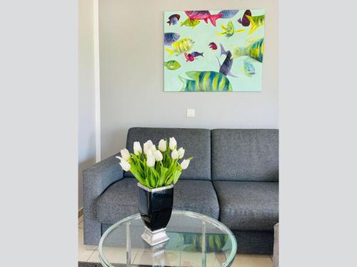 a living room with a couch and a glass table with flowers at Apartment Potosi Teichhof Fehmarn in Wenkendorf