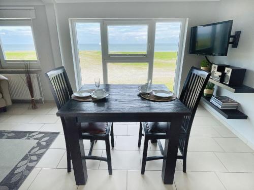 a dining room with a table with chairs and a television at Apartment Potosi Teichhof Fehmarn in Wenkendorf