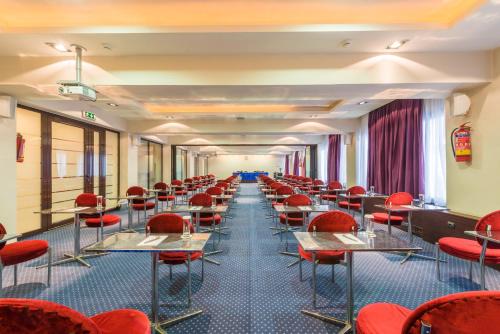 a row of tables and chairs in a room with red chairs at Queen Olga Hotel in Thessaloniki