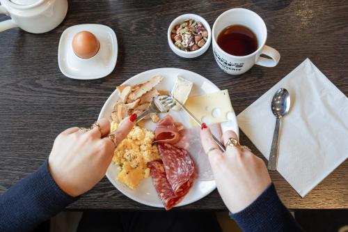 a person eating a plate of breakfast food on a table at Kyriad Rennes Nord Hotel in Rennes