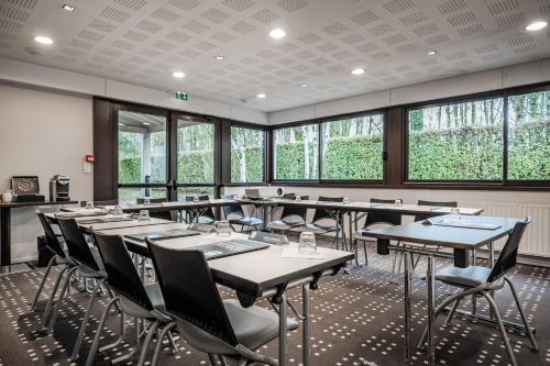 a dining room with tables and chairs and windows at Kyriad Rennes Nord Hotel in Rennes