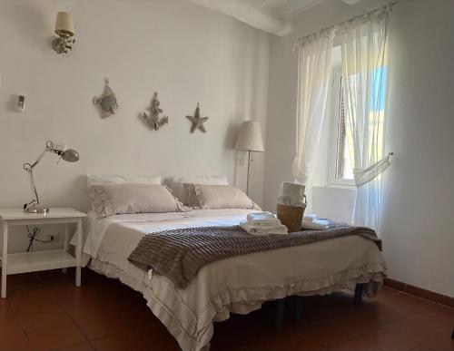 a white bedroom with a bed and a window at Little Medieval House Nettuno in Nettuno