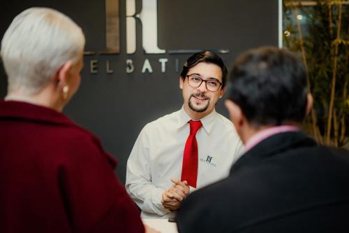 a man wearing a red tie talking to two men at Hotel Batista in Posadas