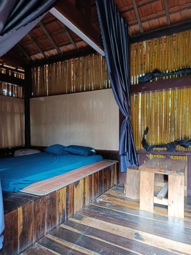 a bedroom with a bed and a table in it at A Vũ Homestay & Coffee in Kon Cho Dri