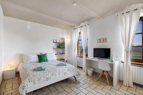 a bedroom with a bed and a desk and a television at B_B La Rugiada in Tigliole