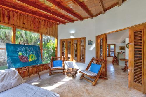 a living room with a bed and chairs and windows at Río Mar Cumayasa in La Romana
