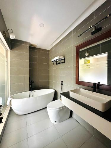 a bathroom with a tub and a toilet and a sink at My Marina Beach Hotel Phu Quoc in Phú Quốc