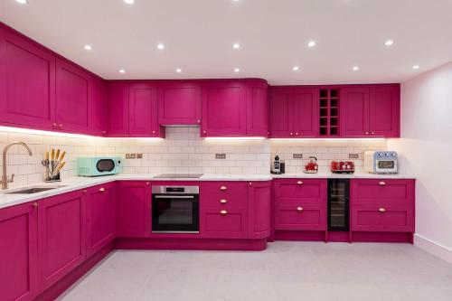 a purple kitchen with white counters and appliances at Luxury Apartment next to Parliament Square in London