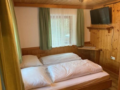 a bedroom with two beds and a window and a television at Haus Martin Appartement Eichhörnchen in Ramsau am Dachstein