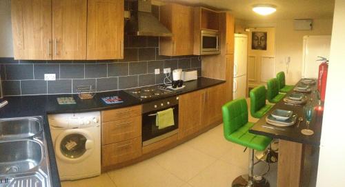 una cocina con armarios de madera y sillas verdes en Alton Apartments en Bradford
