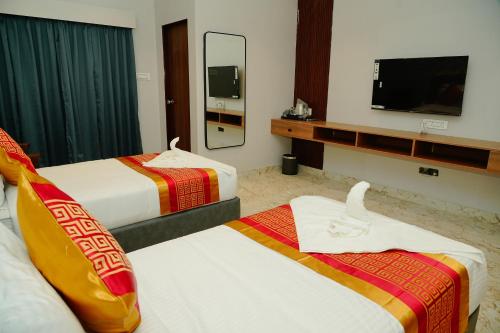 a hotel room with two beds and a flat screen tv at AAryavarth suites 46 in Pālasmudram