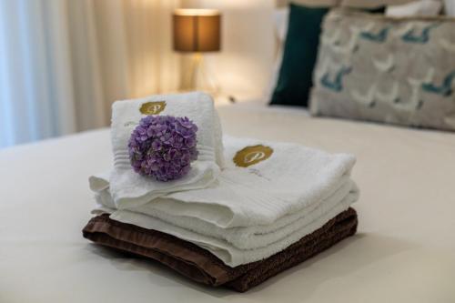 a pile of towels with a purple flower on a bed at GuestReady - Passal Guesthouse in Ponta Delgada
