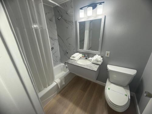 a bathroom with a toilet and a sink and a mirror at Naval Suites by FairBridge in Bremerton