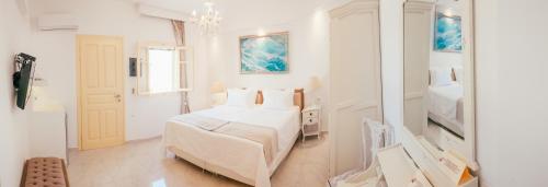a white bedroom with a bed and a mirror at The White Suites in Adamas