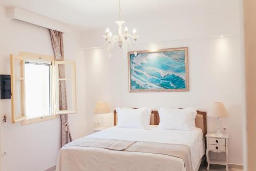 a white bedroom with a bed and a window at The White Suites in Adamas