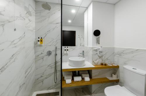 a white bathroom with a sink and a shower at TURIM Santa Maria da Feira Hotel in Santa Maria Da Feira