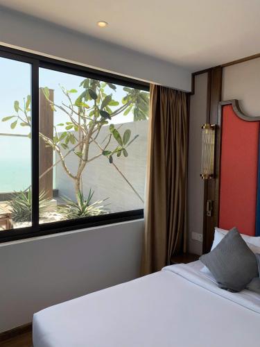 a bedroom with a bed and a large window at Apec Mandala Wyndham ChamBay Mui Ne - LT in Mui Ne