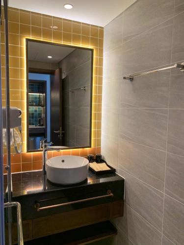 a bathroom with a sink and a mirror at Apec Mandala Wyndham ChamBay Mui Ne - LT in Mui Ne