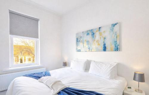 a white bed in a white bedroom with a painting on the wall at The Norton Apartment by GR Estates in Stockton-on-Tees