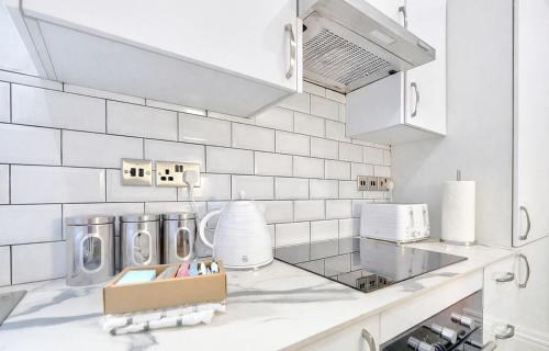 a kitchen with white tiled walls and white appliances at The Norton Apartment by GR Estates in Stockton-on-Tees
