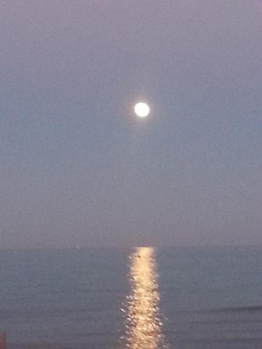 a moon rising over the ocean at night at Terrazzo sul mare in Donnalucata