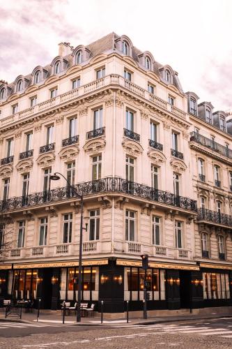 un grand bâtiment blanc dans une rue de la ville dans l'établissement L'Aventure Hôtel, à Paris