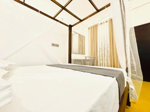 a white bed in a white room with a window at Lucky Eagle Nest in Tangalle
