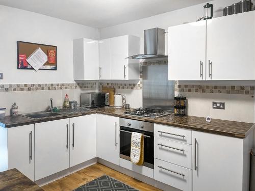 a kitchen with white cabinets and a stove top oven at Miner's Rest in Frizington
