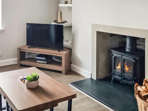 a living room with a fireplace with a television and a table at The Shore in Fortrose