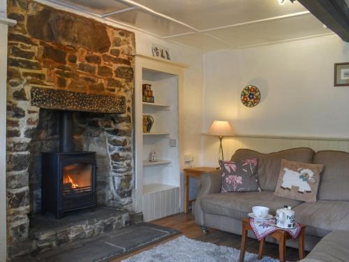 a living room with a stone fireplace and a couch at Horseshoe Cottage in Starbotton
