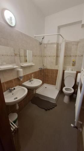 a bathroom with two sinks and a toilet and a shower at MAMRE Szálló in Hajdúböszörmény