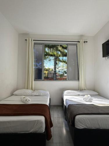three beds in a room with a window at HOTEL PUERTO DULCE - La Virginia in La Virginia