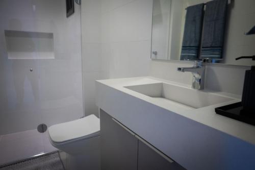 a white bathroom with a sink and a toilet at Studio Completo Perto Hospital e Shopping in Tubarão