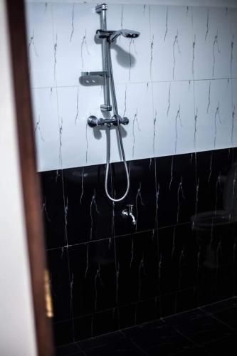 a shower in a bathroom with a black and white tiled wall at Lagoonvilla hotel in Ambalangoda
