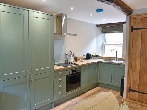 a kitchen with green cabinets and a sink at 14 Doomgate House - Uk45055 in Appleby