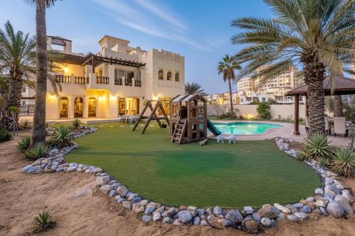 a yard with a playground in front of a house at 5 Bedroom Villa with Pool - Near Al-Marjan Island in Ras al Khaimah