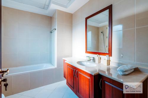 a bathroom with a sink and a mirror and a tub at 5 Bedroom Villa with Pool - Near Al-Marjan Island in Ras al Khaimah