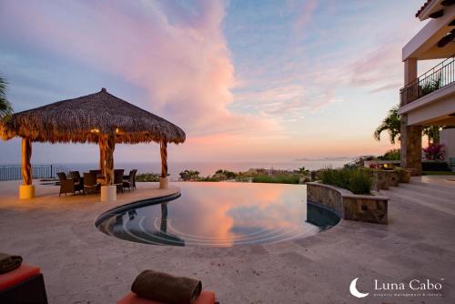 a swimming pool with a straw umbrella and a resort at Puerto Los Cabos Villa - Infinity Pool & Hot Tub in San José del Cabo
