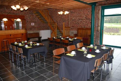 a dining room with tables and chairs and a brick wall at Ferme du Charme in Moustier