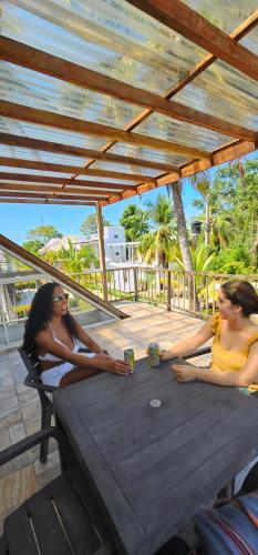 two women sitting at a wooden table with drinks at cabañas Brisas y Perla by AMAUNA in Moñitos