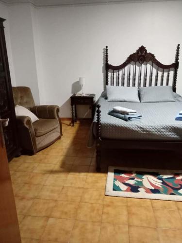 a bedroom with a bed and a chair and a rug at Moradia Lili in Ronqueira