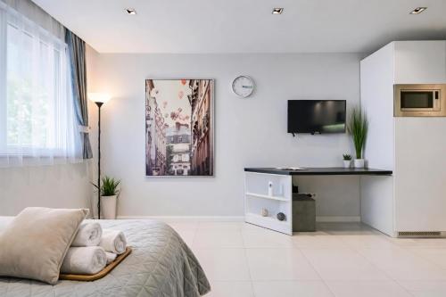 a white bedroom with a bed and a tv at N9 Studentski Loft - Cozy Apt with Private Parking in Sofia
