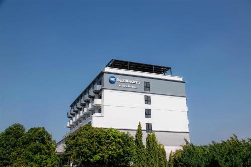 a white building with trees in the foreground at Best Western Matter Tiwanon Hotel in Bangkok