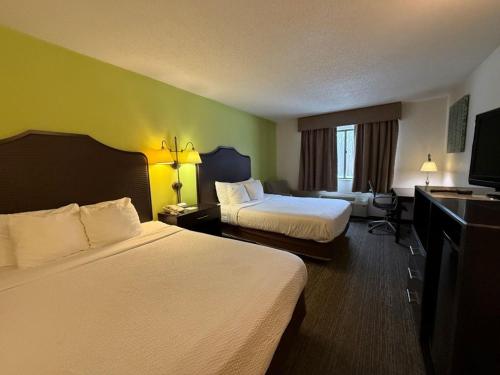 a hotel room with two beds and a flat screen tv at SureStay by Best Western Grove City in Grove City