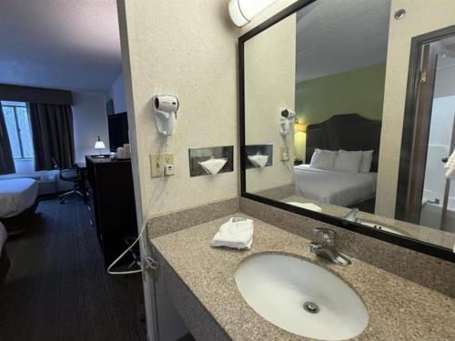 a bathroom with a sink and a large mirror at SureStay by Best Western Grove City in Grove City